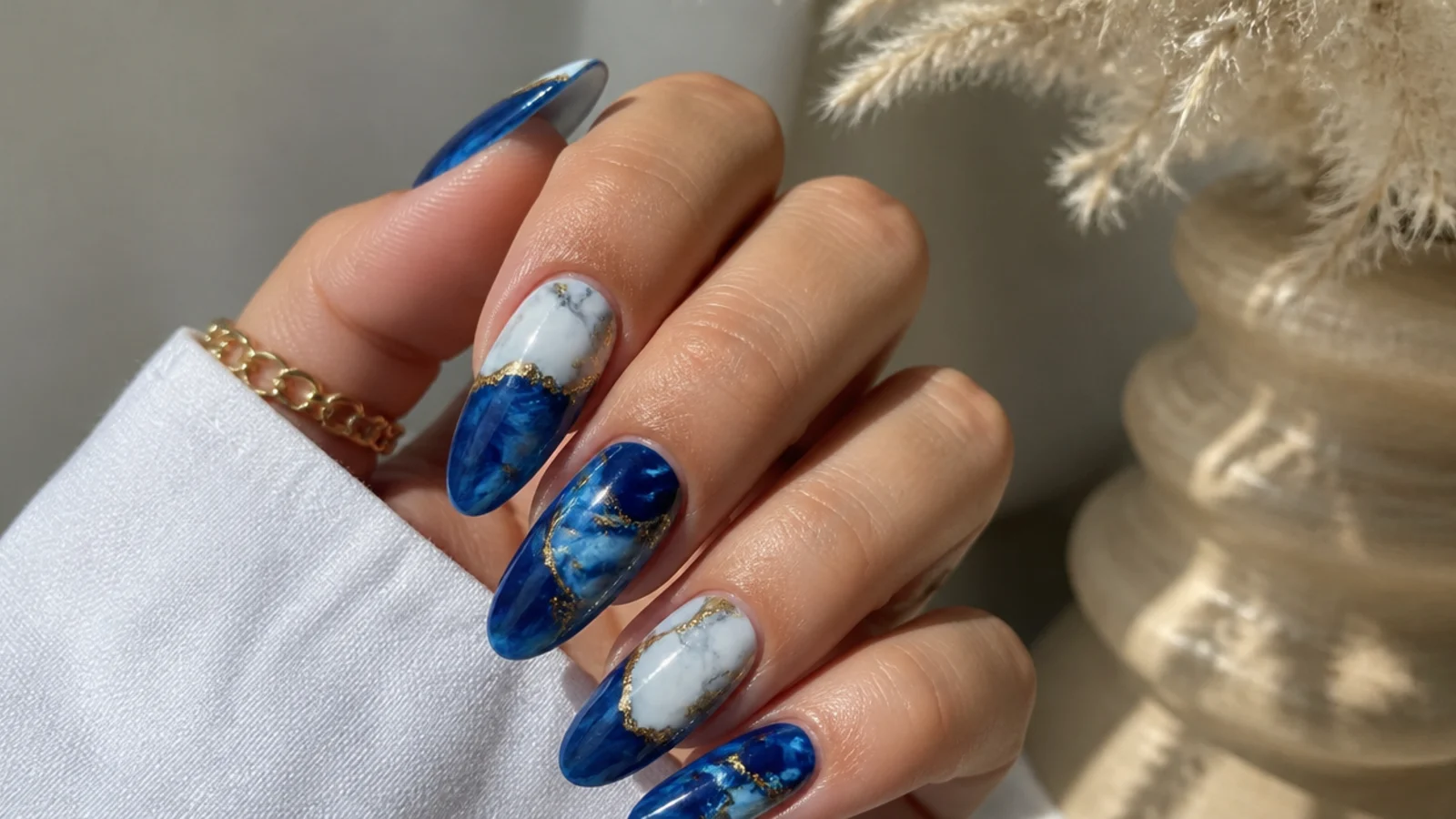 Royal blue and white marble acrylic nails with thin gold veins on almond nails
