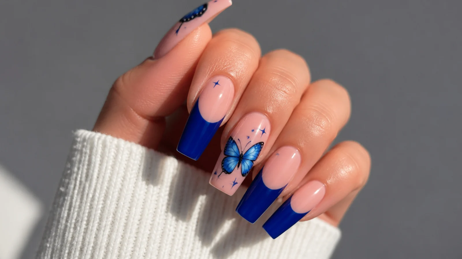 Royal blue acrylic nails with a hand-painted blue butterfly accent on coffin nails