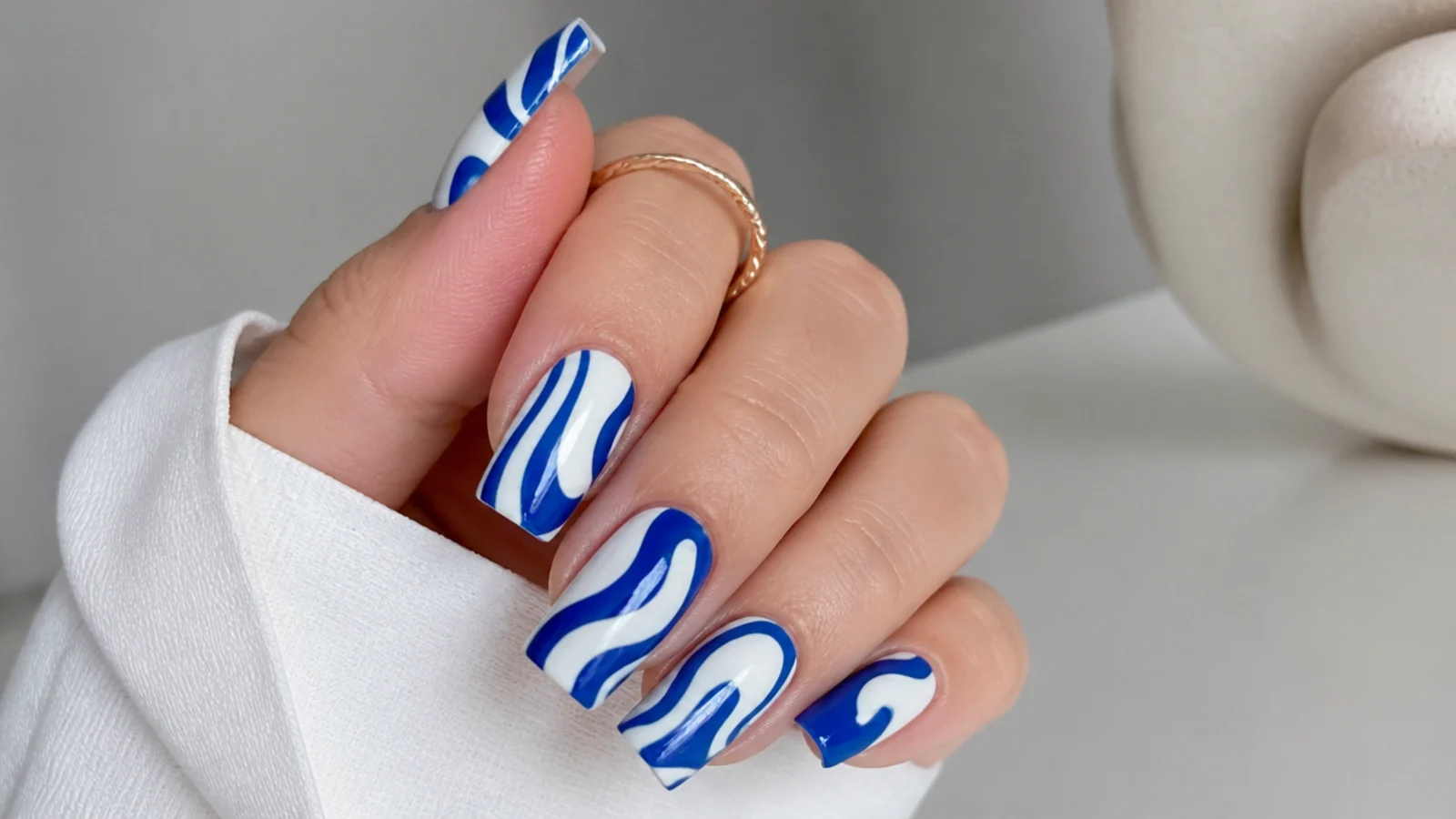 Royal blue and white swirl acrylic nails in a retro pattern on square nails