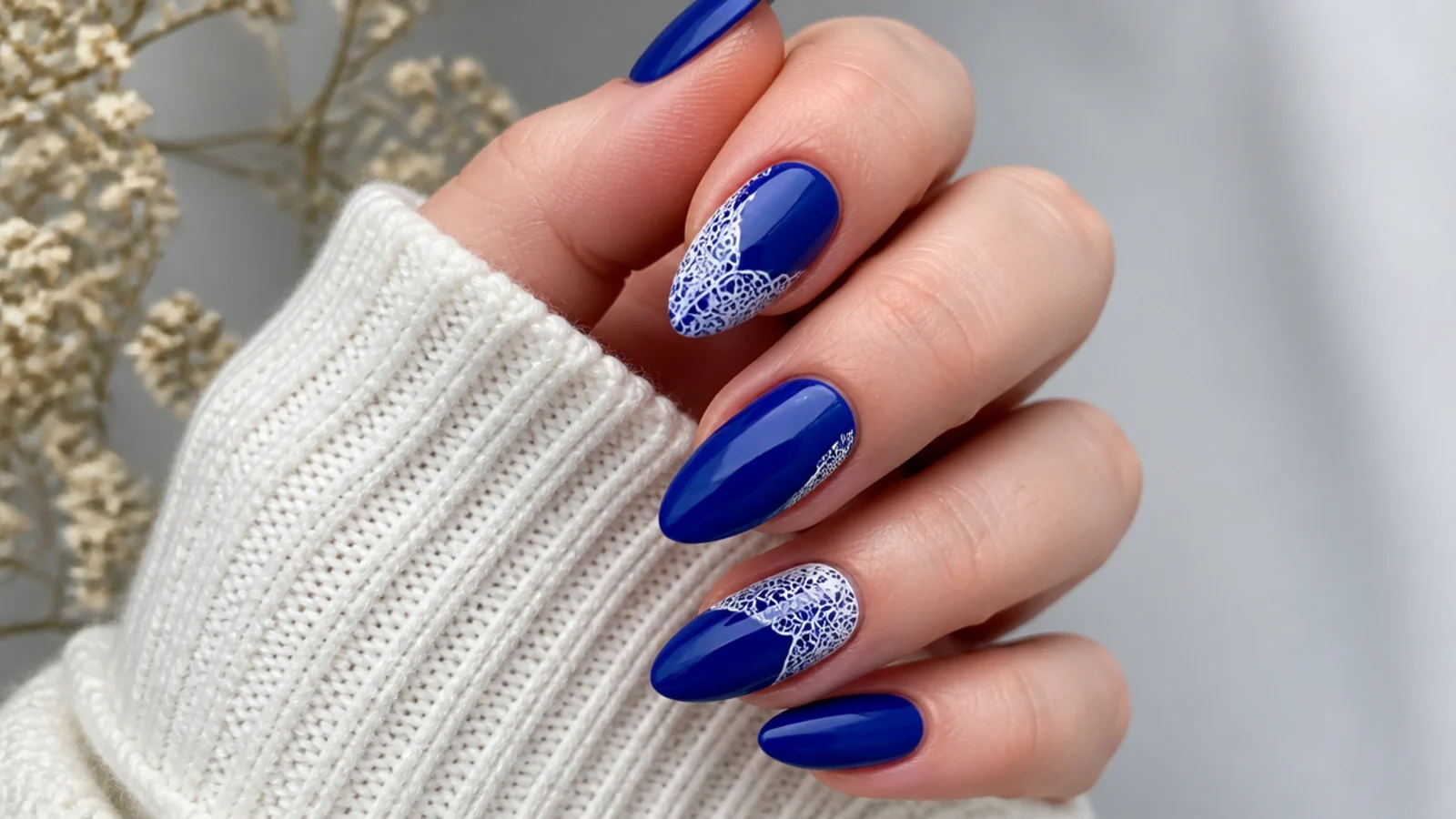 Royal blue acrylic nails with delicate white lace detailing on almond nails