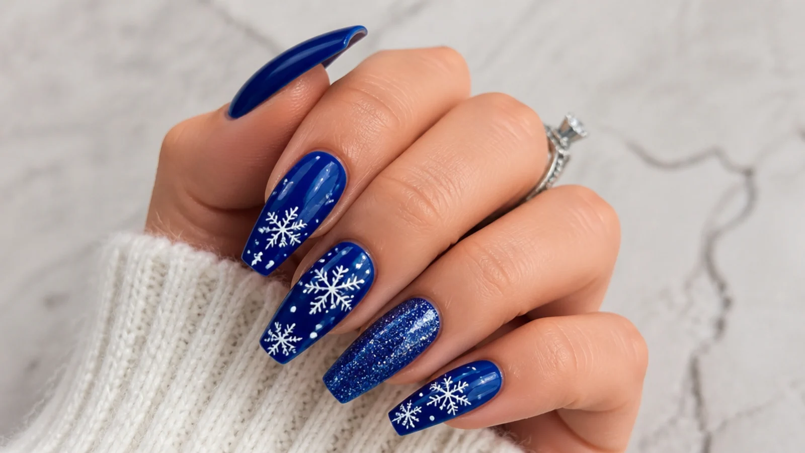 Royal blue acrylic nails with white snowflake accents for winter on coffin nails