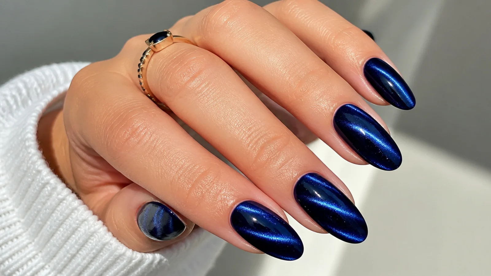 Deep royal blue almond nails with a magnetic cat-eye shimmer stripe