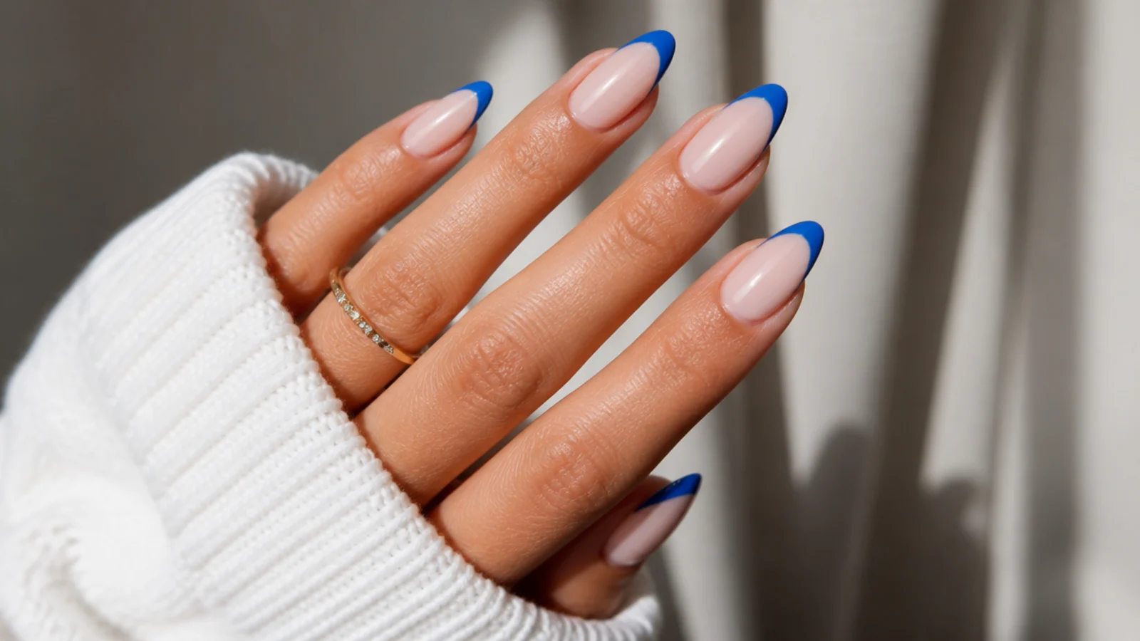 Sheer nude almond nails with crisp royal blue french tips