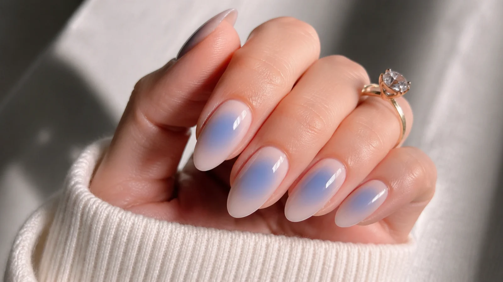 Sheer nude almond nails with a soft royal blue aura glow at the center