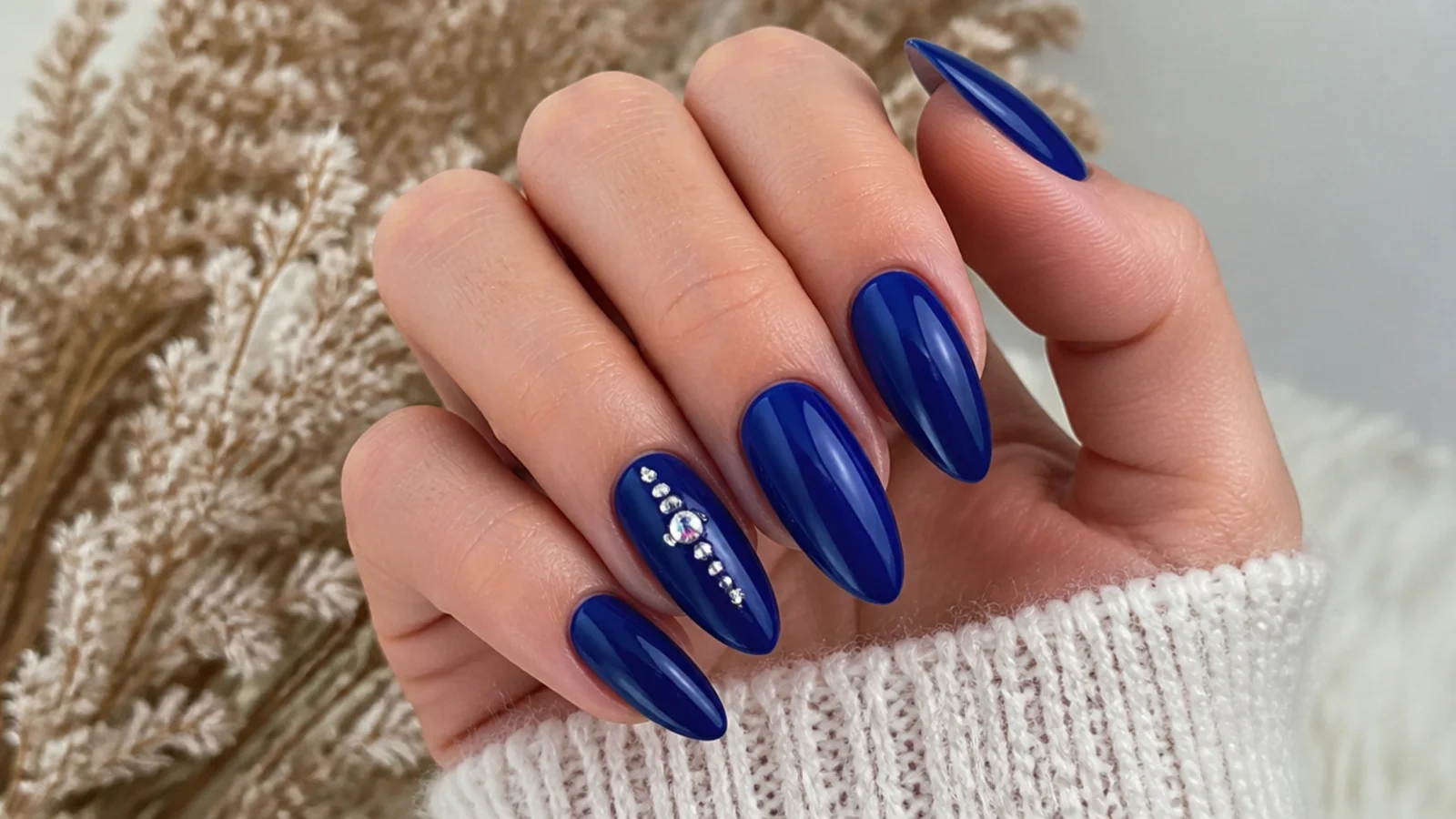 Long deep royal blue almond nails with a single rhinestone accent nail