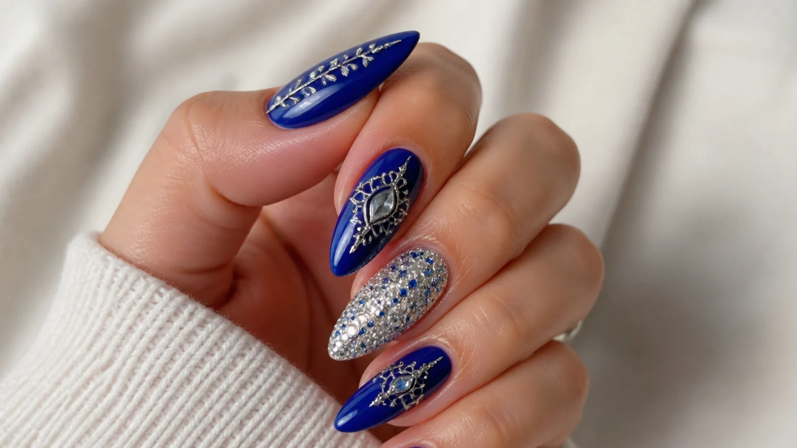 Royal blue almond nails with ornate silver and rhinestone detailing