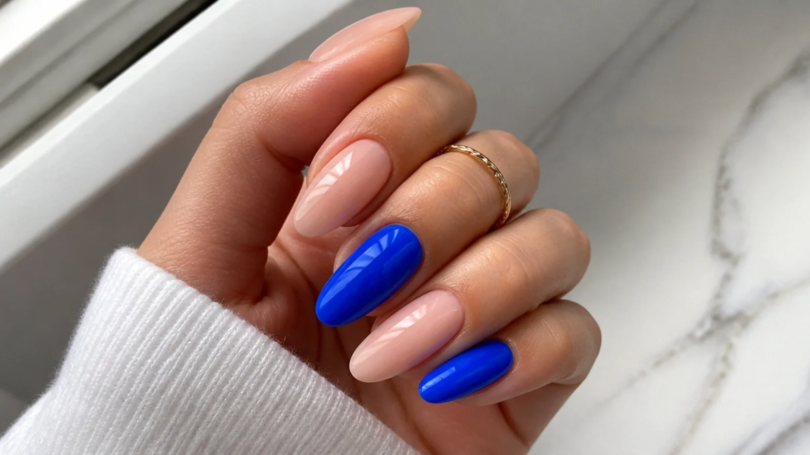 Nude almond nails with two bright electric cobalt blue accent nails