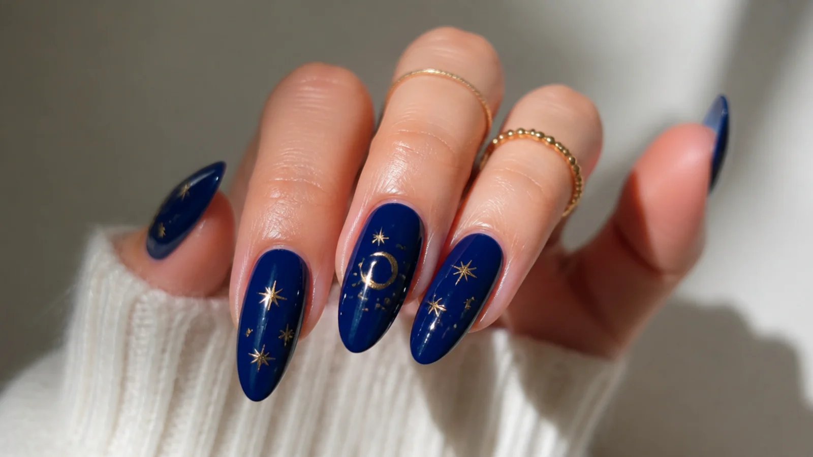 Deep royal blue almond nails with tiny gold star and moon details