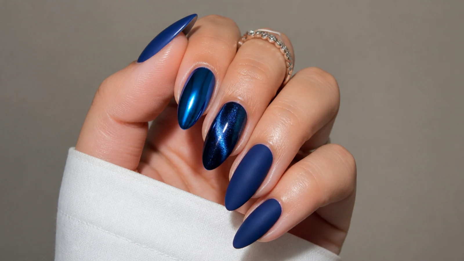 Glossy, chrome, cat-eye and matte royal blue almond nails side by side