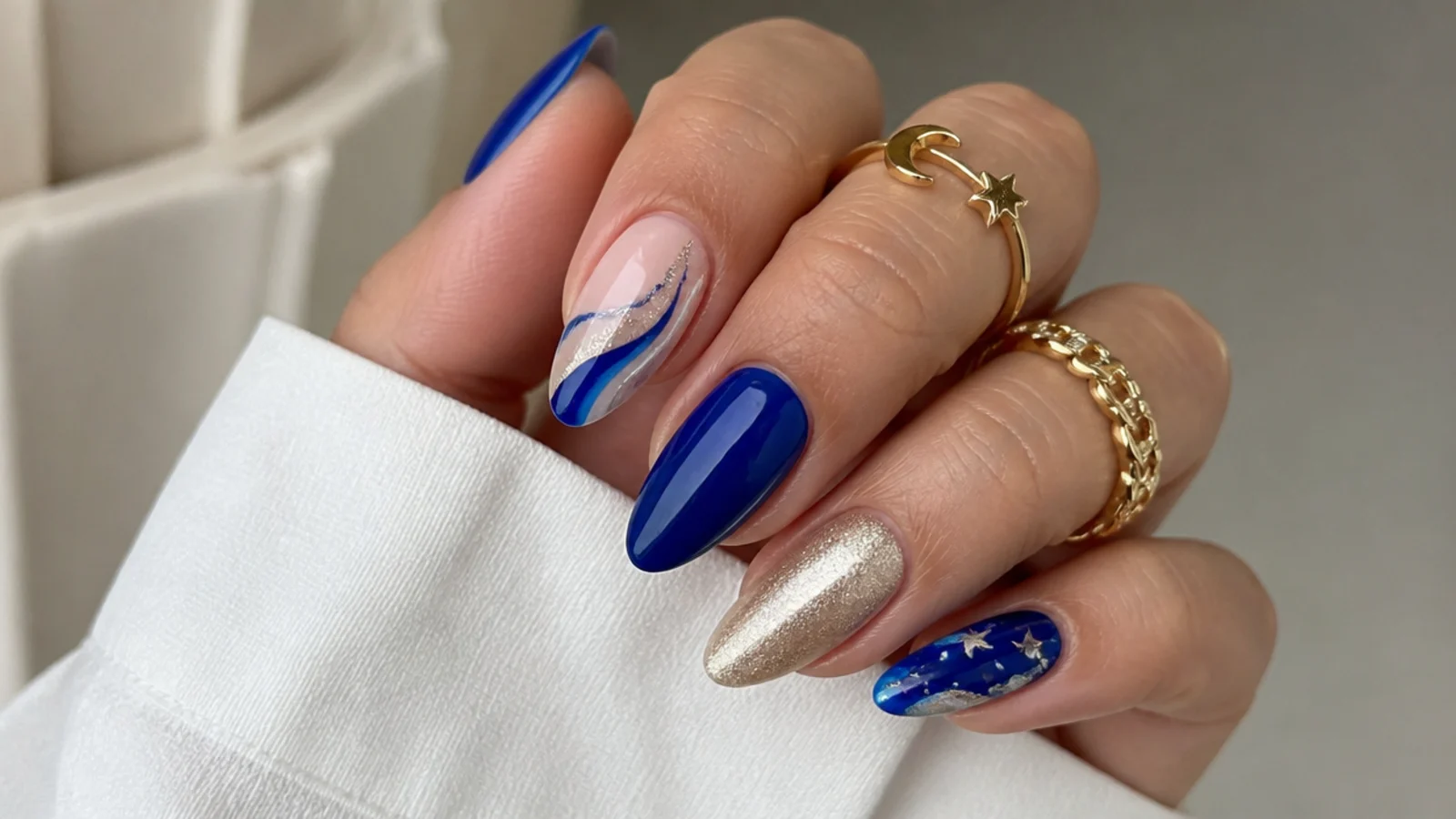 Royal blue almond nails paired with gold, silver, white and nude accents