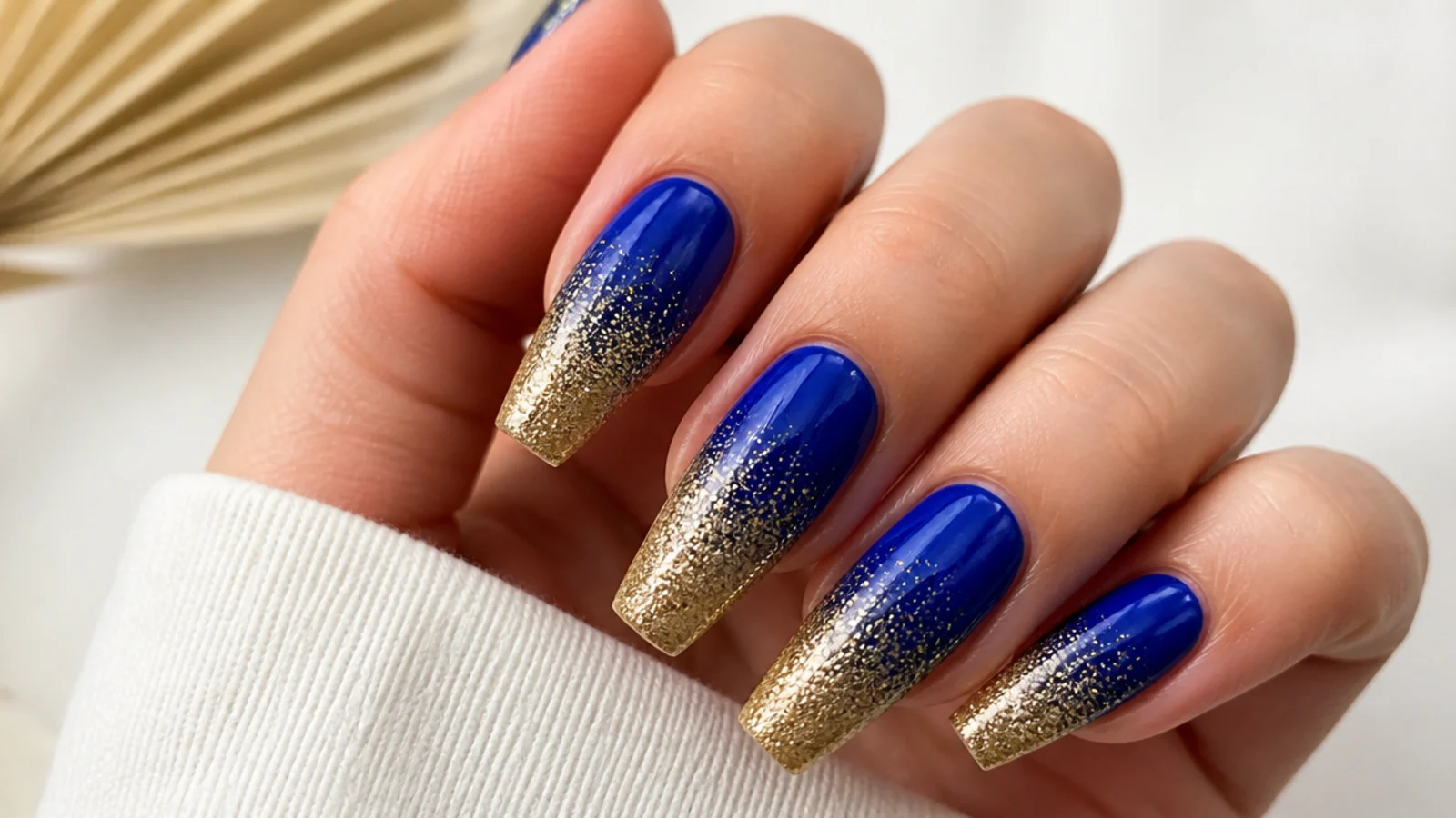 Royal blue nails fading into gold glitter at the tips on coffin nails