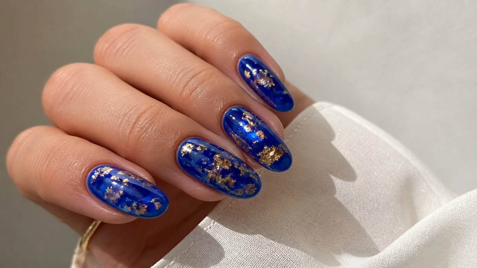 Sheer royal blue jelly nails suspending gold flakes for a resin look
