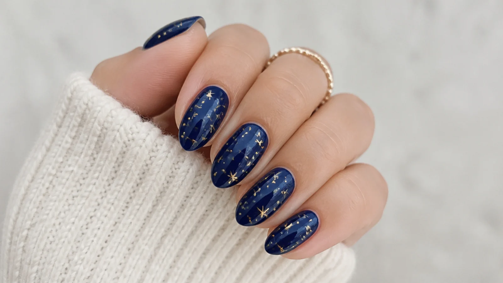 Deep royal blue nails scattered with tiny gold stars and dots
