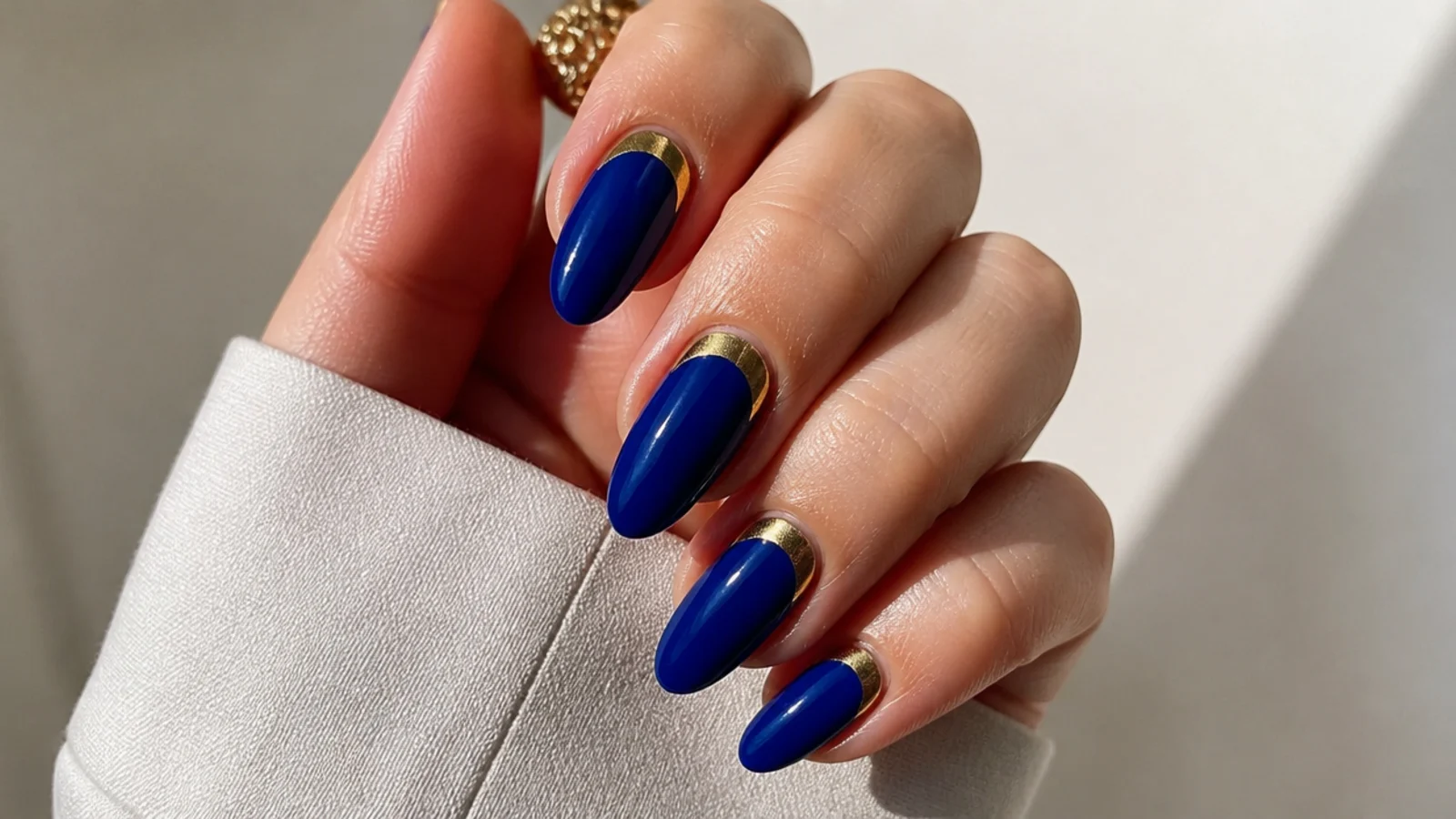 Royal blue nails with gold half-moon cuticle arcs on almond nails