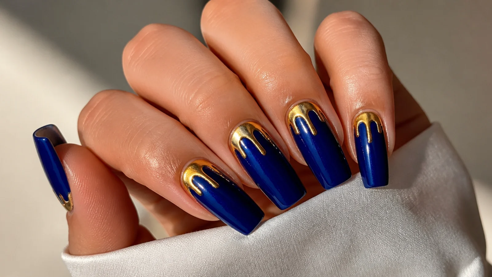 Royal blue nails with molten gold chrome drips from the cuticle