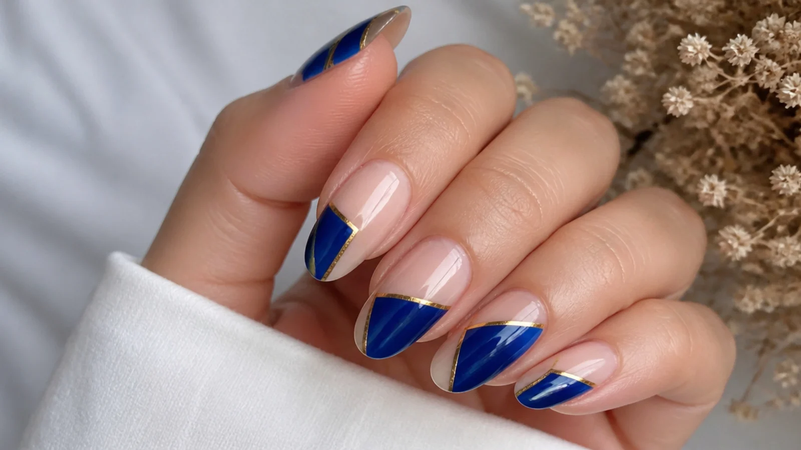 Clear nails with royal blue geometric shapes edged in gold lines