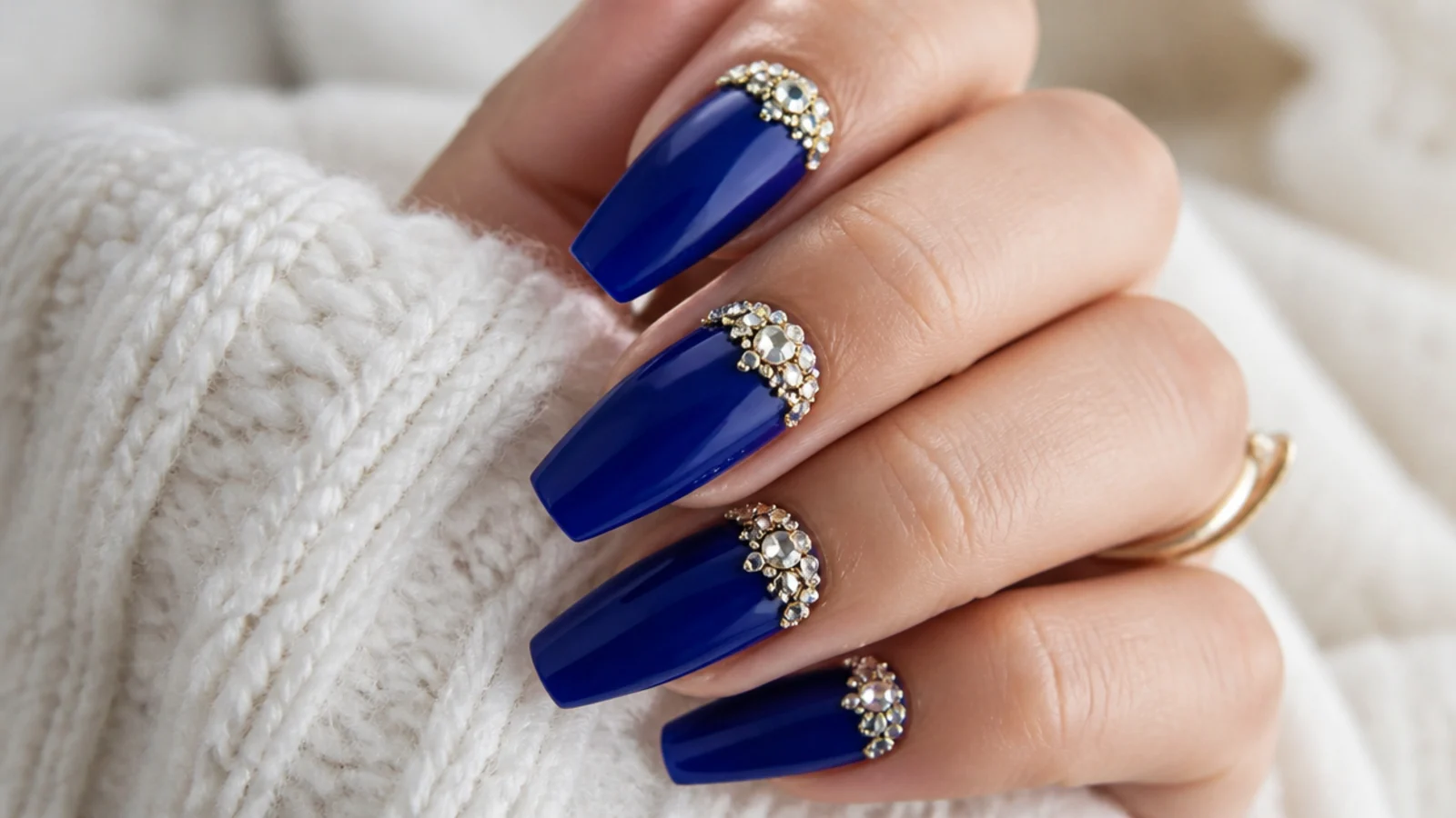 Royal blue nails with a cluster of gold rhinestones and gems near the cuticle
