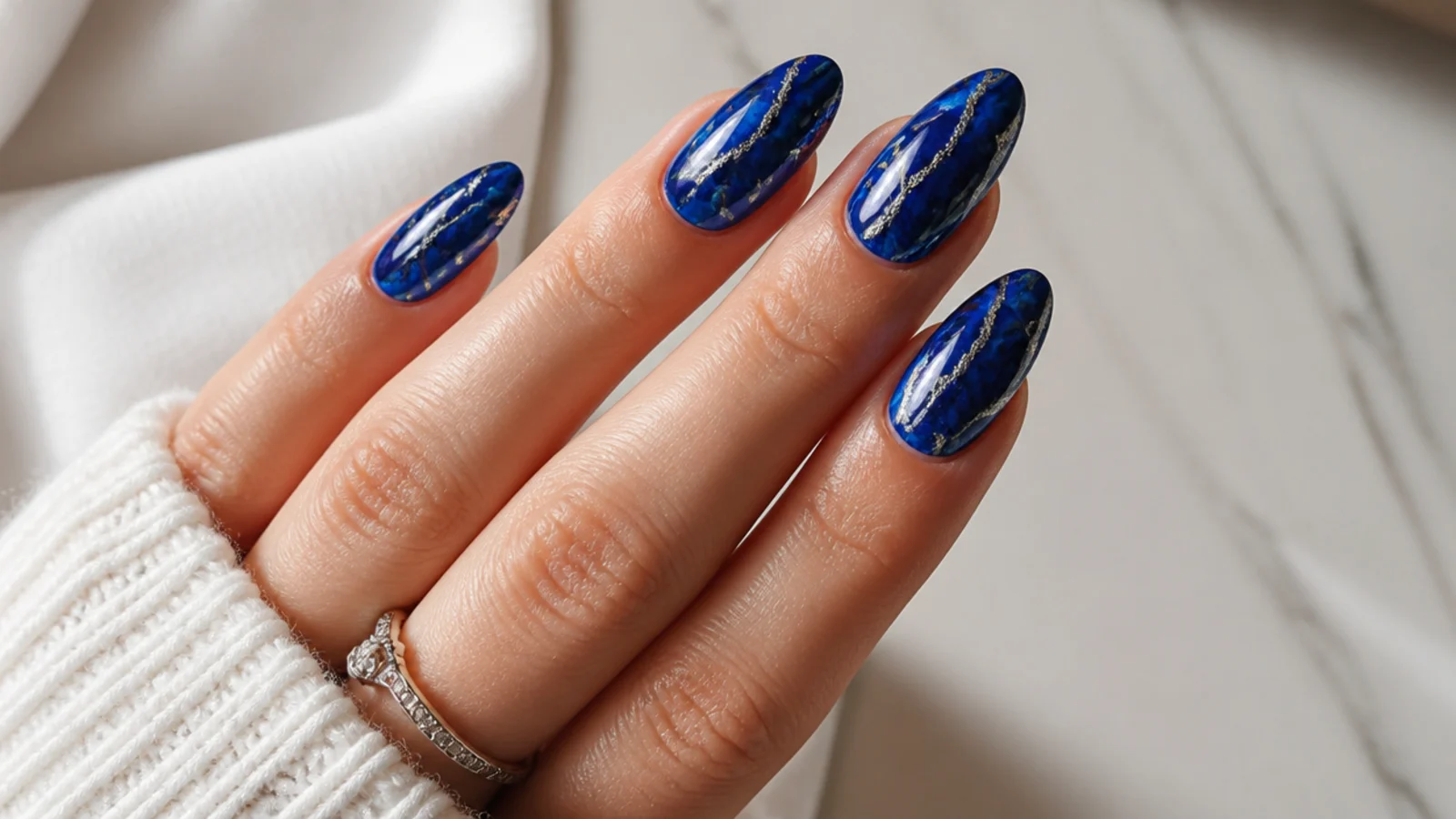 Royal blue nails with silver foil veining in a marble pattern