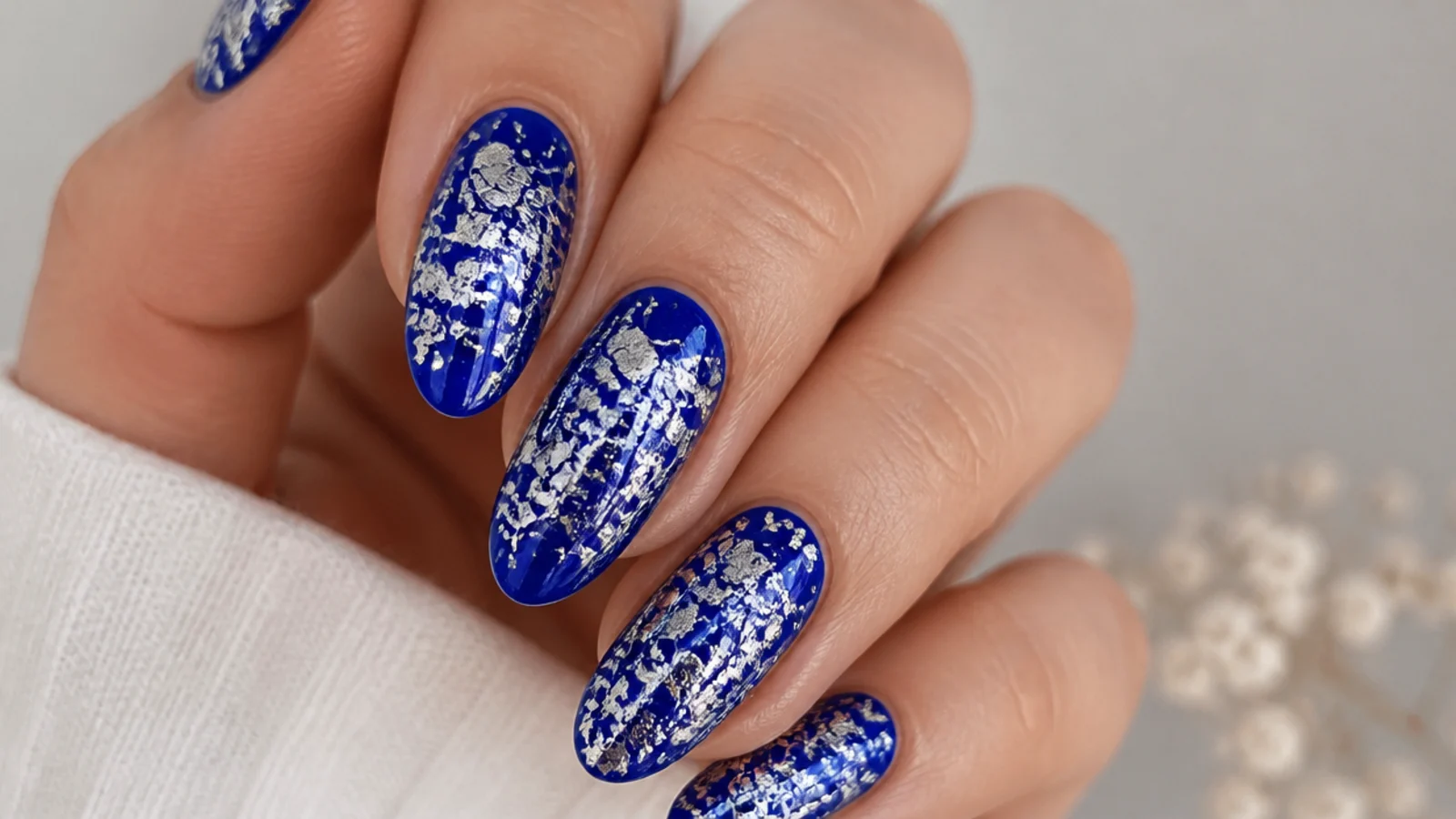 Royal blue nails with cracked silver foil shattered across the surface