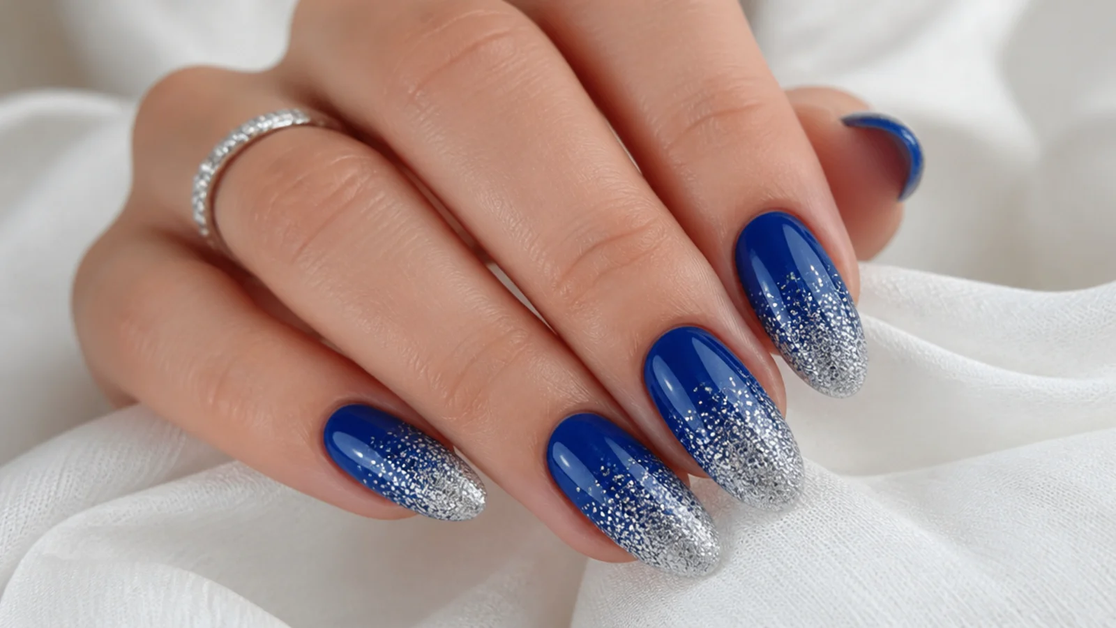 Royal blue nails fading into dense silver glitter at the tips