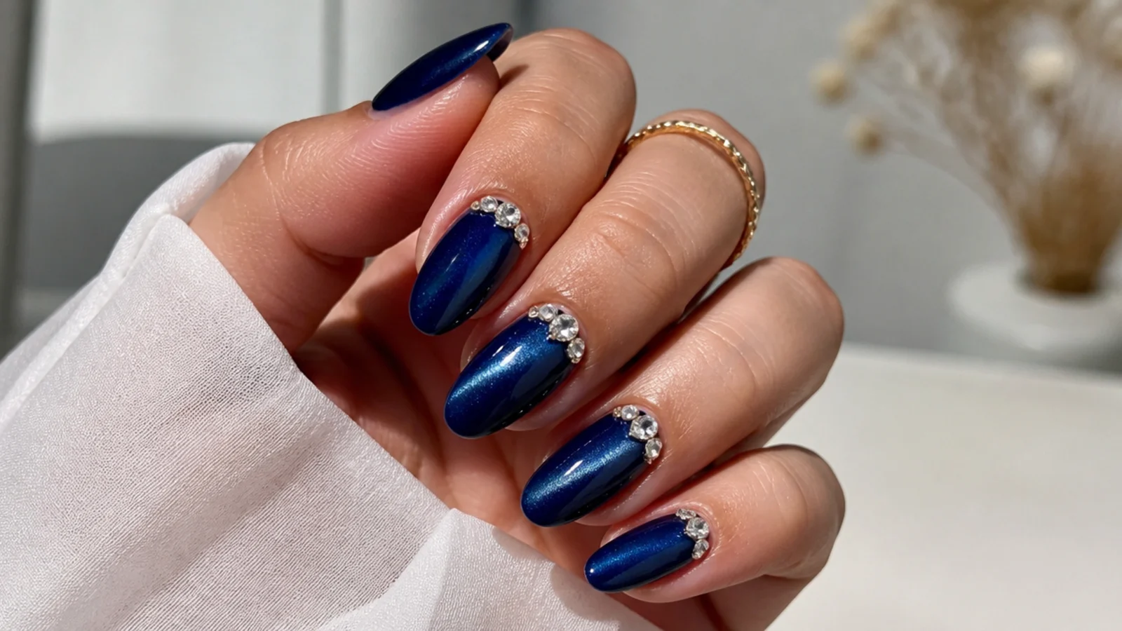 Royal blue cat eye nails with clustered clear crystals near the cuticle