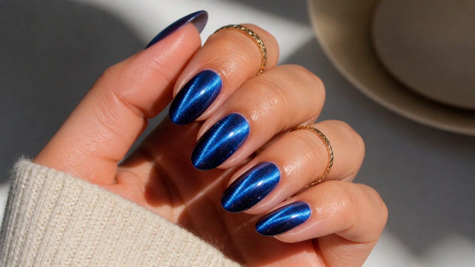 Royal blue cat eye nails with a bright magnetic light strip across an almond shape