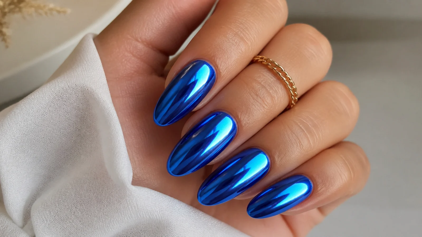 Full mirror royal blue chrome nails on an almond shape reflecting light