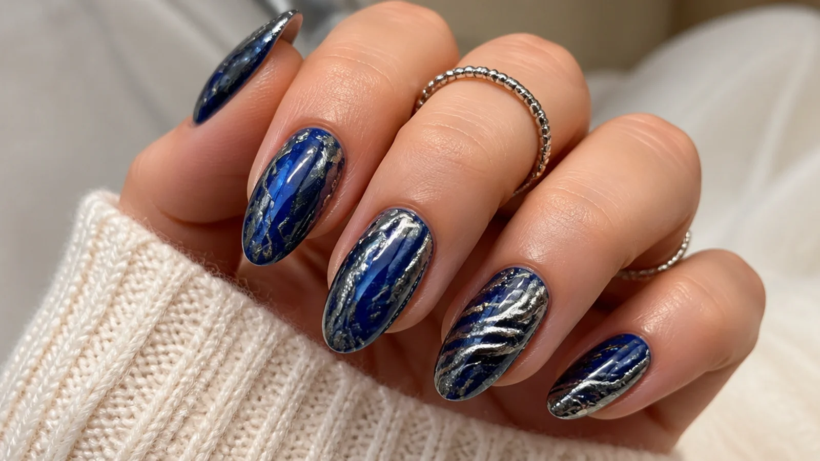 Royal blue and silver chrome marble nails with swirling metallic veins