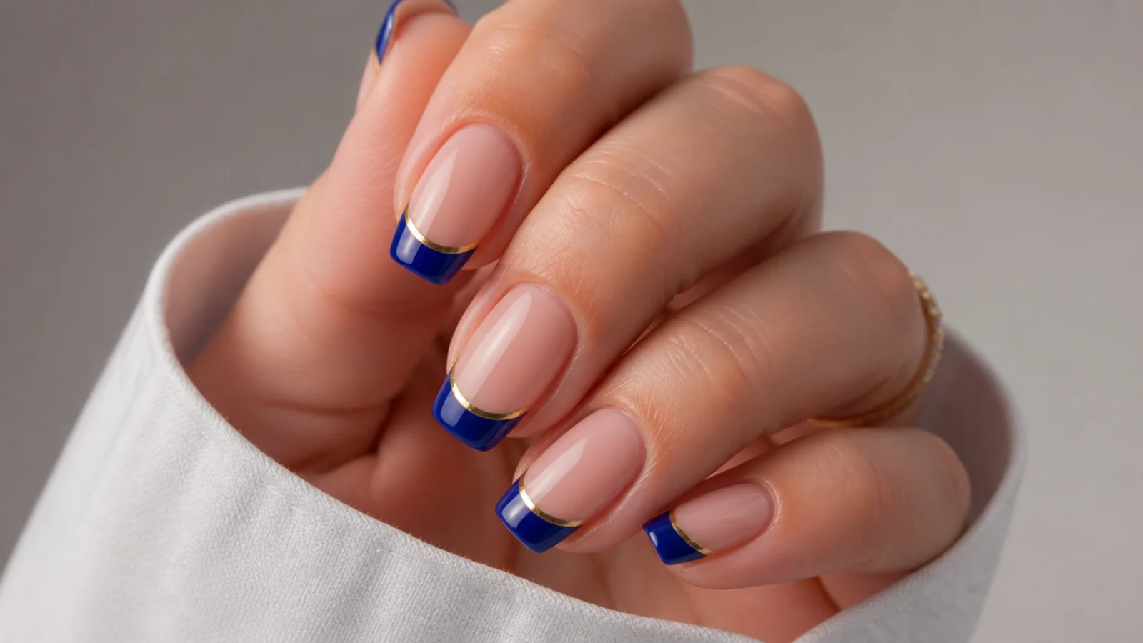 Royal blue french tips lined with thin gold foil on a nude base