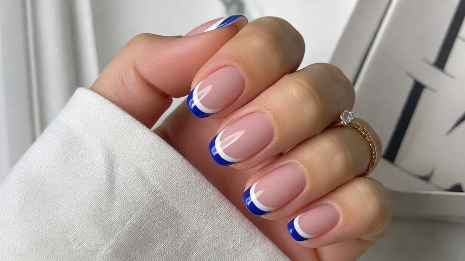 Double french tip nails with a white line above a royal blue tip