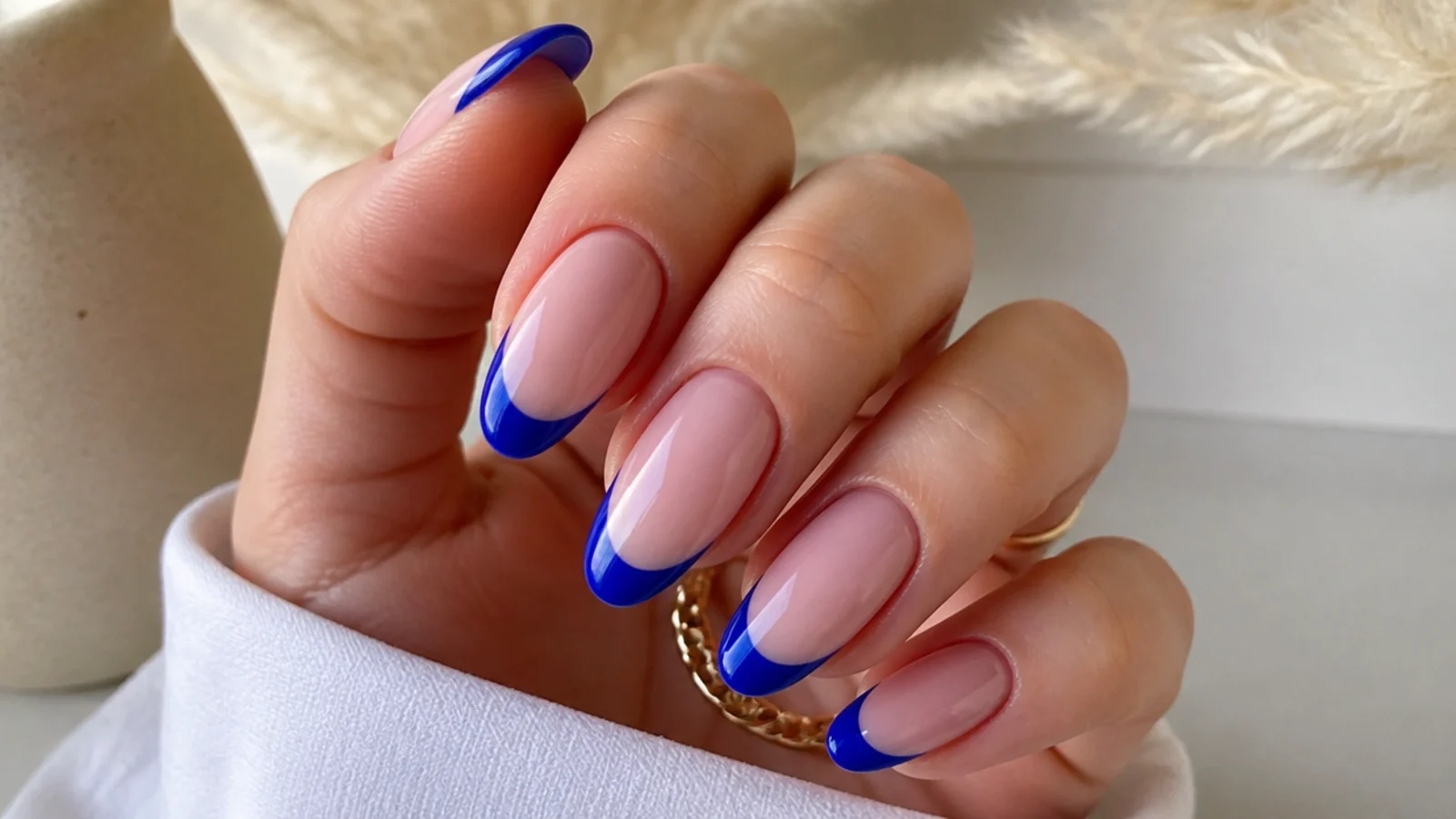 Glossy royal blue french tip nails on an almond shape over a nude base