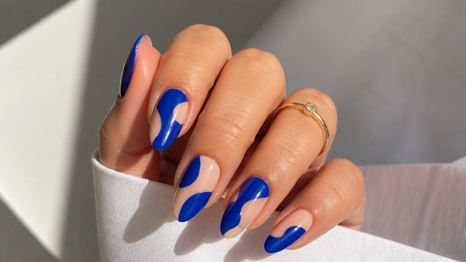 Royal blue negative-space nails with bare nude gaps and blue shapes