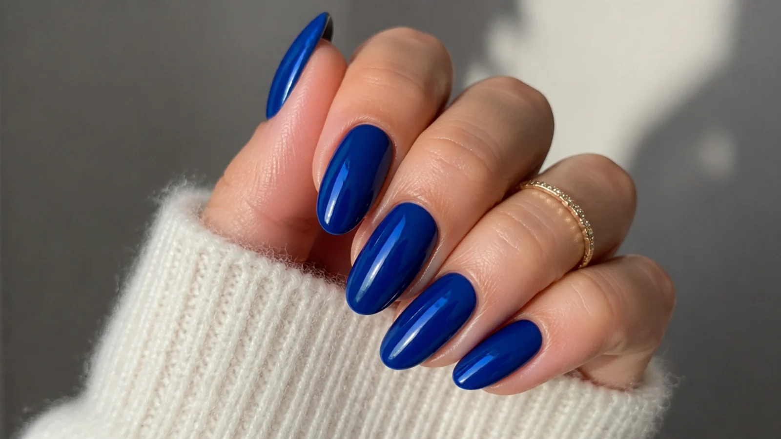 Long royal blue almond nails with a glossy finish