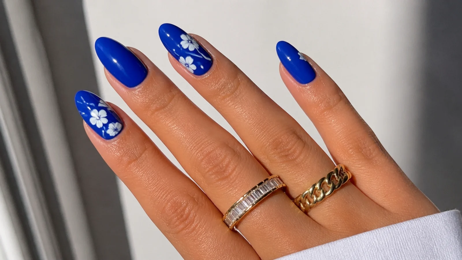 Bold royal blue nails in a glossy almond shape on medium skin