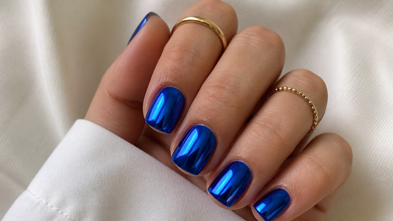 Short square nails in mirror-chrome royal blue with a reflective metallic finish