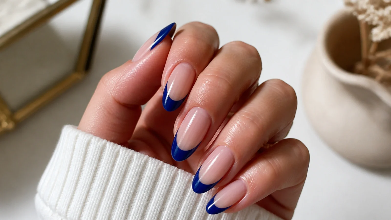 Almond nails with royal blue french tips over a sheer nude base