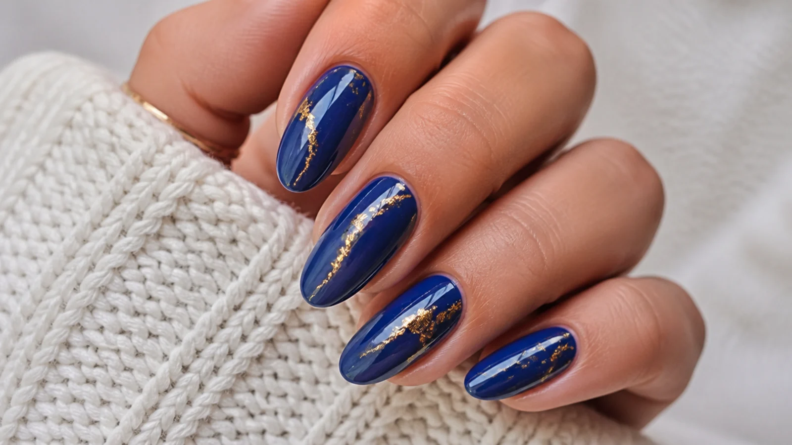 Royal blue nails with thin gold foil accents on a glossy base