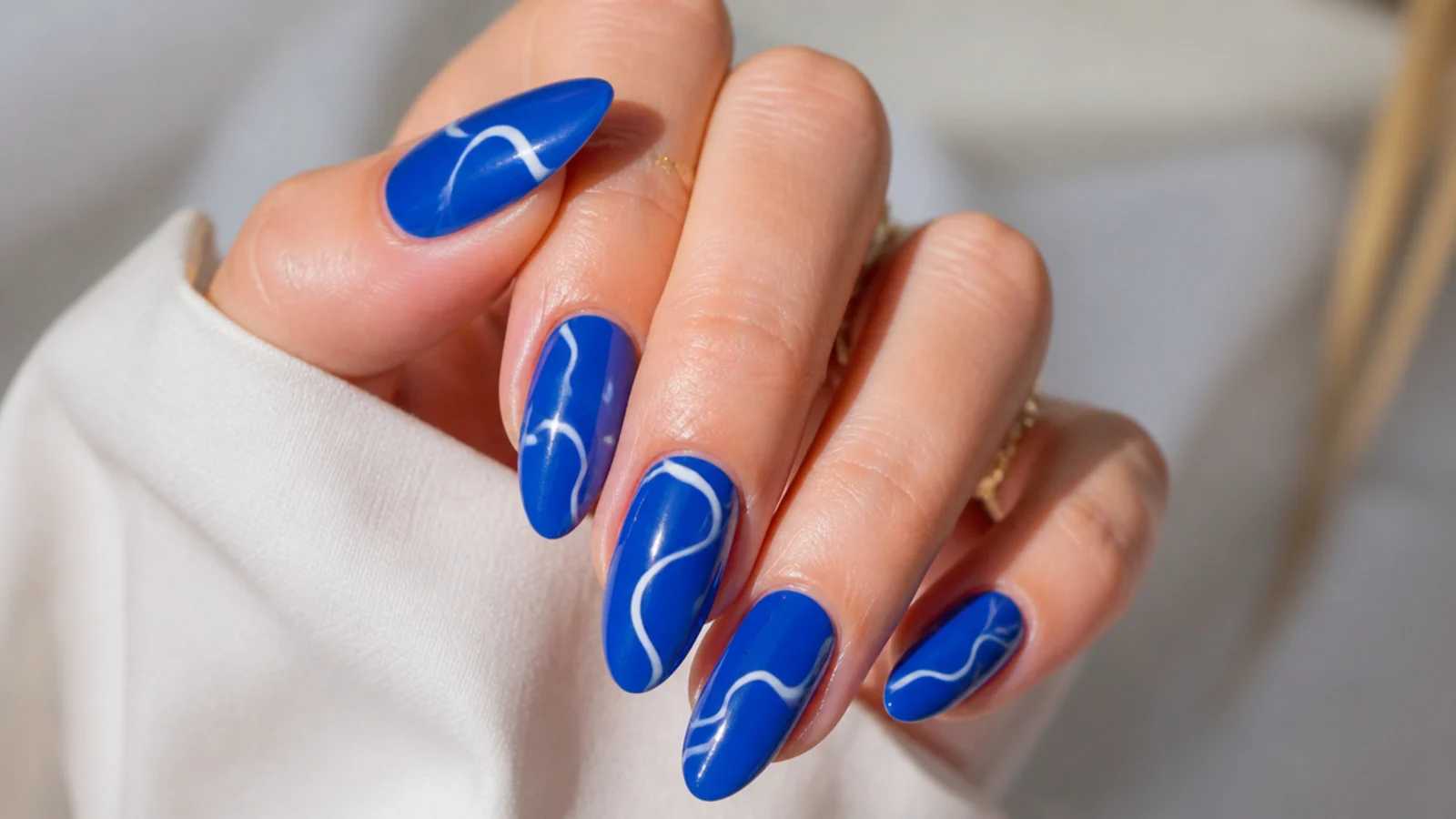 Royal blue nails with wavy white swirl lines on a glossy base