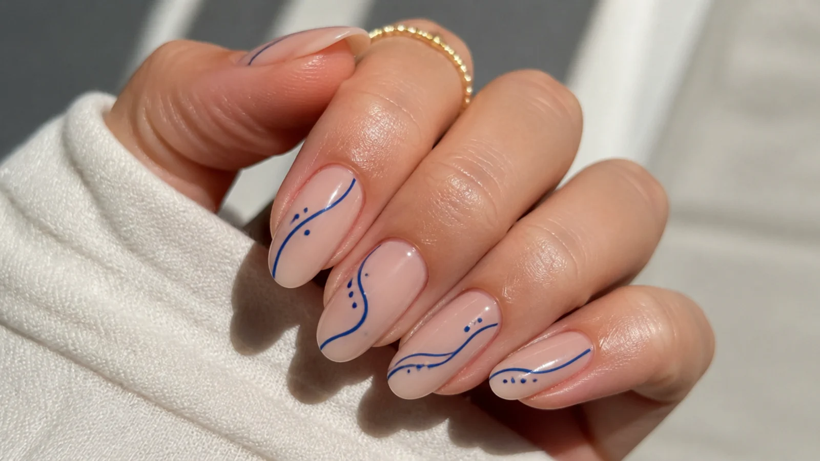 Nude nails with thin royal blue abstract line art and dots