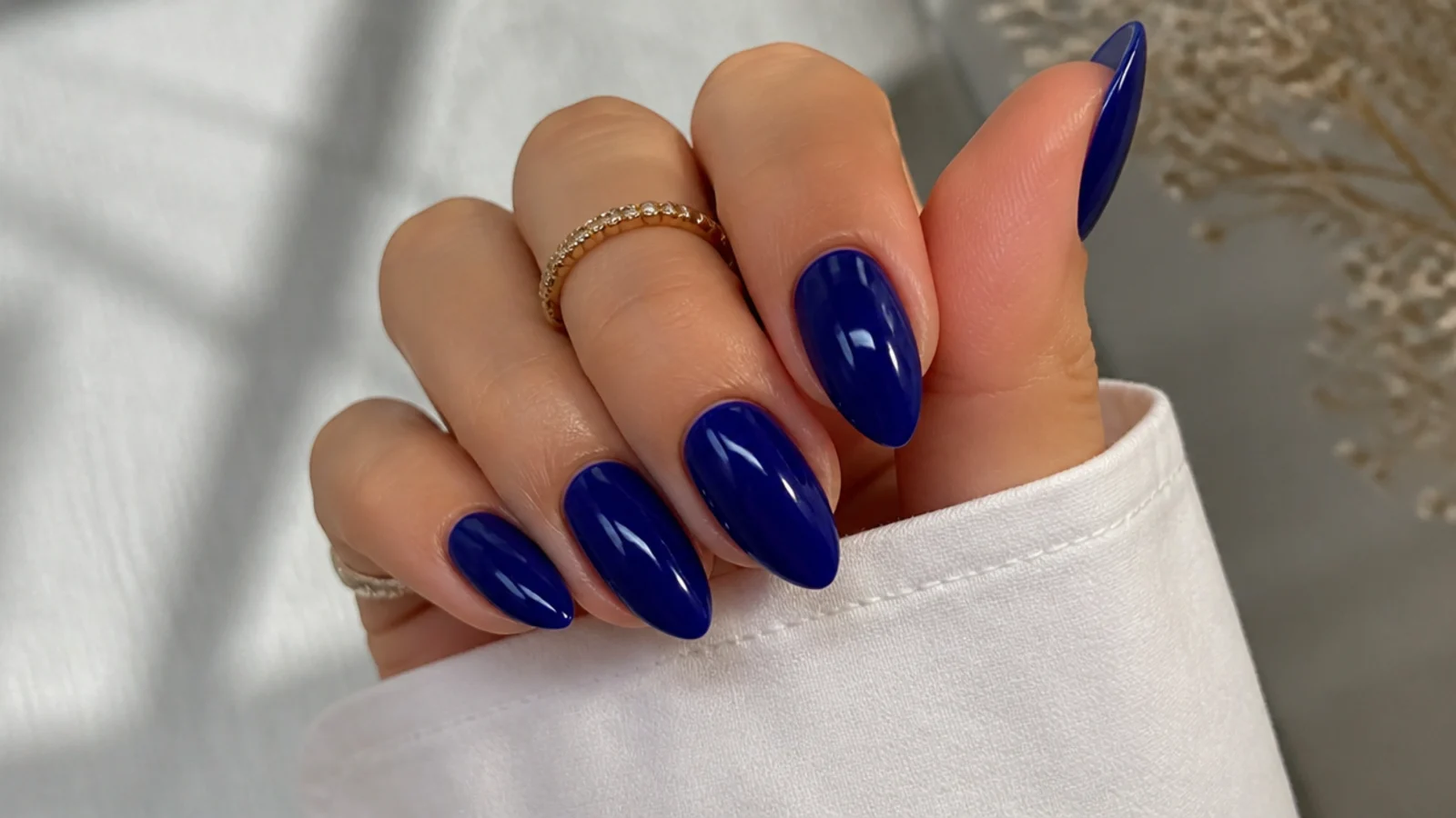Glossy royal blue nails on an almond shape with a deep cobalt finish
