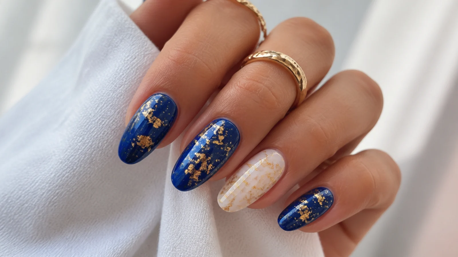Royal blue nails with gold foil flakes and one accent nail