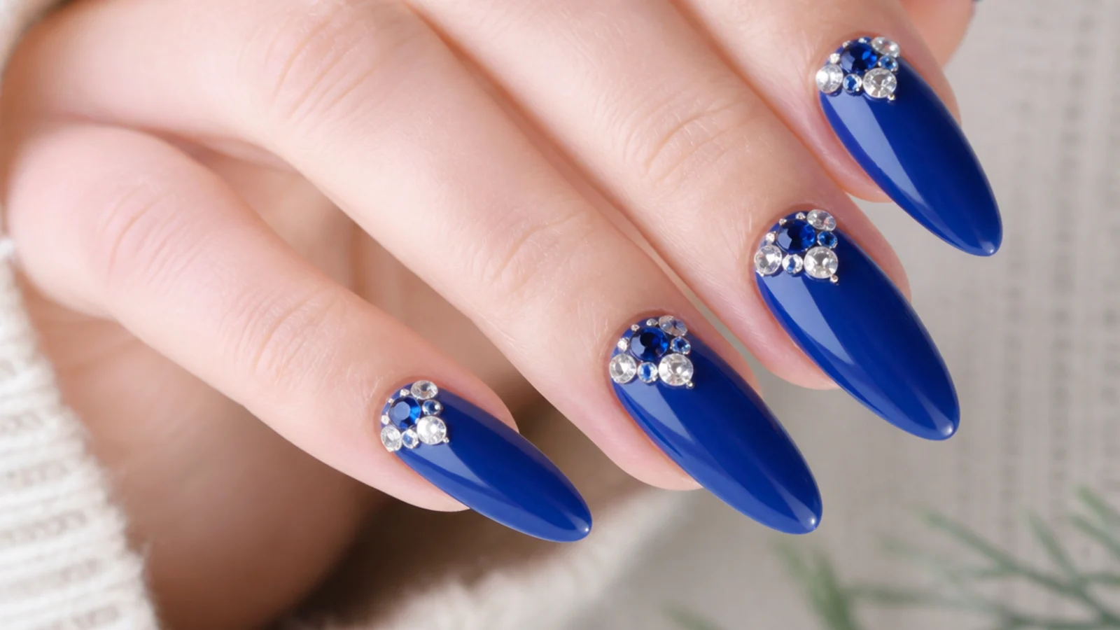 Royal blue nails with clear and blue rhinestone clusters near the cuticle