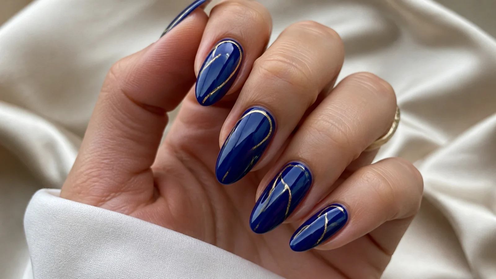 Royal blue nails with thin hand-drawn gold line details