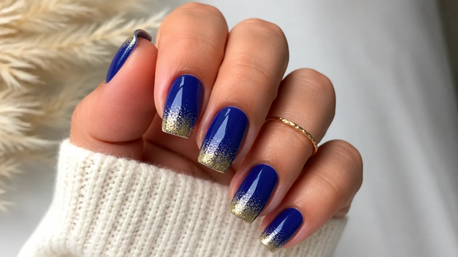 Royal blue nails with a gold glitter ombre fading from the tips