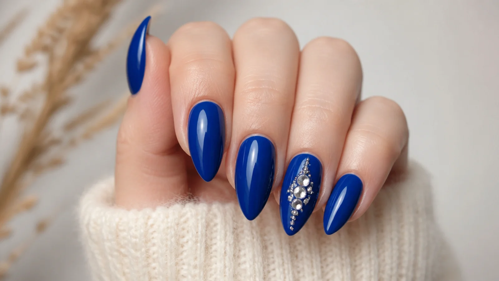 Royal blue almond nails with a silver rhinestone cluster on the ring nail