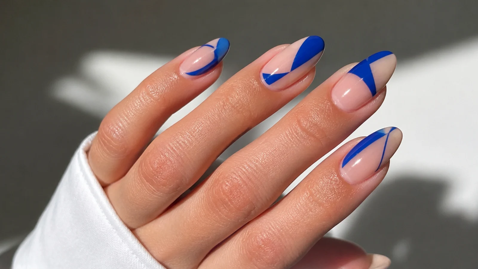 Royal blue geometric shapes over nude negative space nails