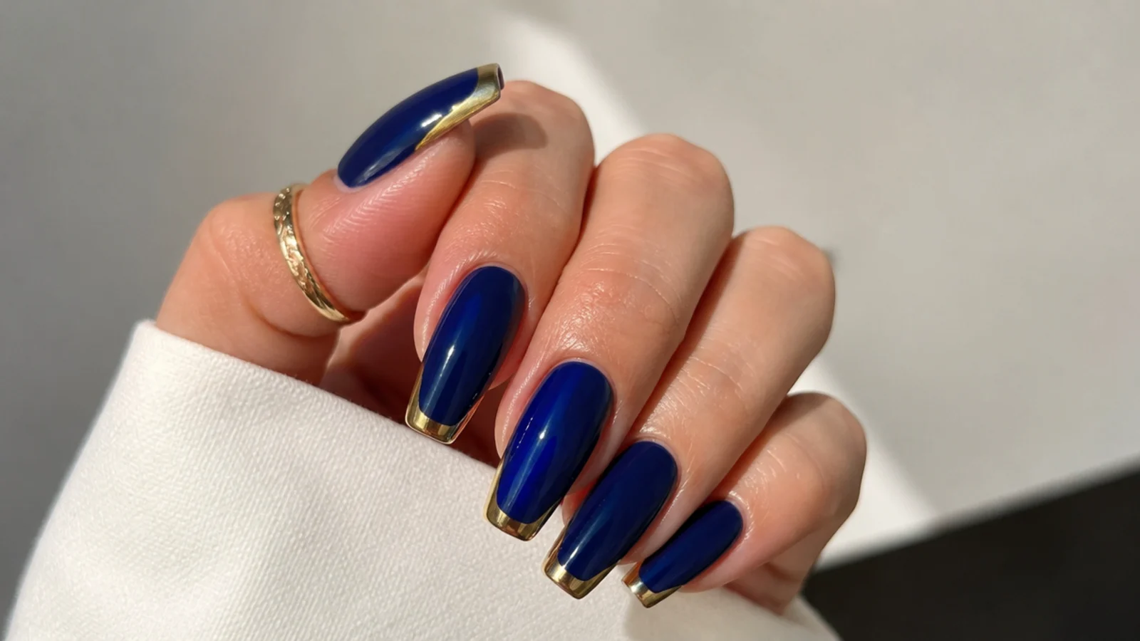 Royal blue nails with metallic gold french tips on a coffin shape