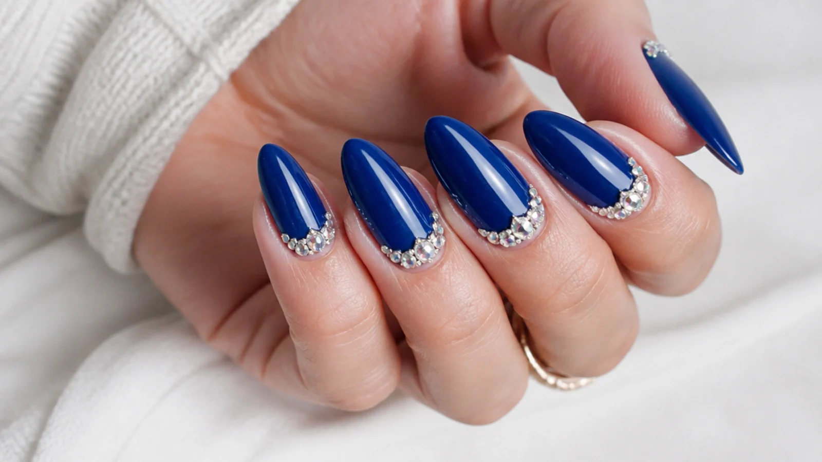 Royal blue nails with a rhinestone crown arch at the cuticle
