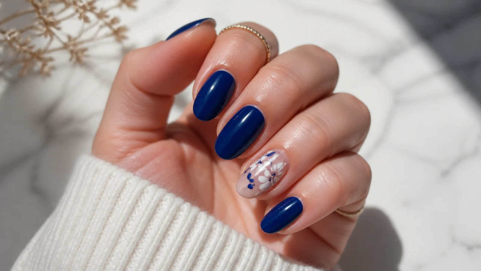 Royal blue nails with hand-painted white flowers on an accent nail