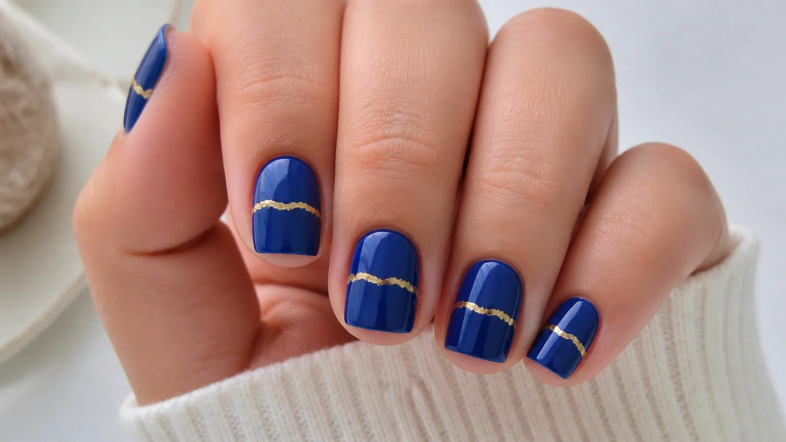 Short royal blue nails with a thin gold foil accent line
